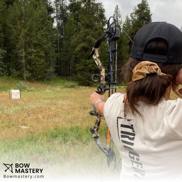 women aiming compound bow towards target