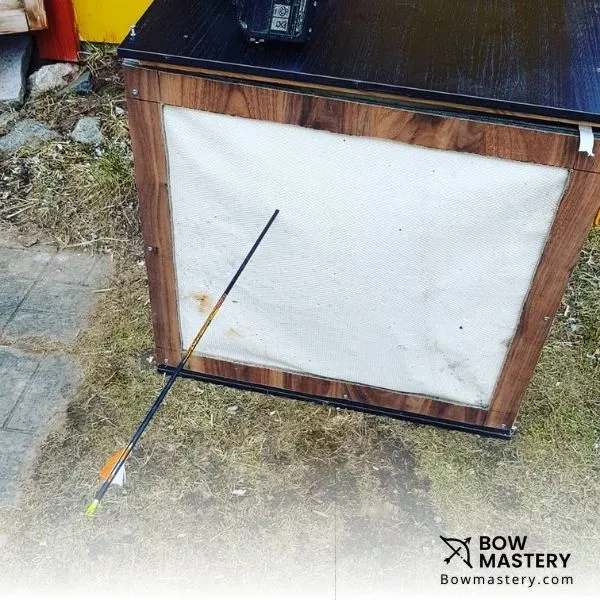 a wooden archery target with arrow in it